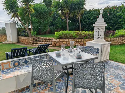 a table and chairs with wine glasses on a patio at Apartamento Páteo - piscina, churrasqueira e vista jardim in Albufeira