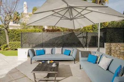 a patio with two blue couches and an umbrella at Villa Grace in Almancil