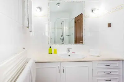 a white bathroom with a sink and a mirror at Villa Katharina in Albufeira