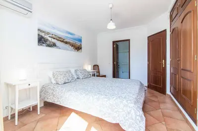 a white bedroom with a bed and a desk at Villa Katharina in Albufeira