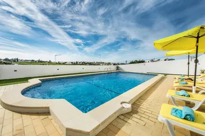a swimming pool with two chairs and an umbrella at Casa Miranda in Albufeira