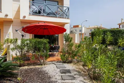 a red umbrella sitting in front of a building at Oleander Terrace Albufeira in Faro