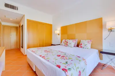 a bedroom with a large white bed with flowers on it at AL - Apartamento Vila Sol N in Vilamoura