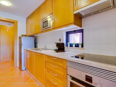 a kitchen with yellow cabinets and a sink and a stove at AL - Apartamento Vila Sol Adaptado in Vilamoura