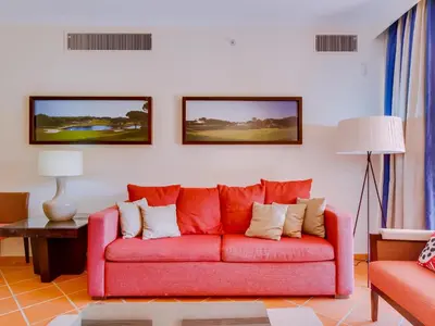 a living room with a red couch and two pictures on the wall at AL - Apartamento Vila Sol Adaptado in Vilamoura