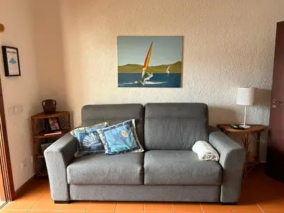 a living room with a gray couch with a surfboard on it at Ouramar Apartment in Albufeira