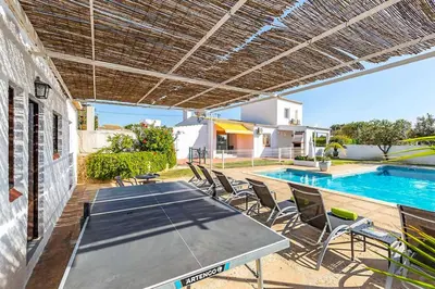 a patio with a table and chairs and a swimming pool at Casa do Engenho in Galé