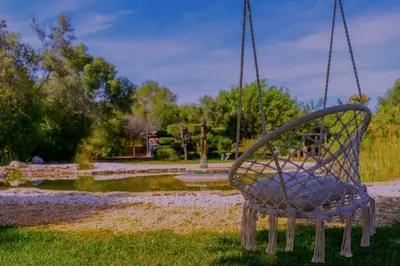 a swinging chair in a park with a pond at The Quinta Retreat Algarve Available to Facilitators yoga & sound therapies, massage mindfulness in Almancil