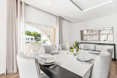 a white dining room with a white table and chairs at Villa Corcovada in Albufeira