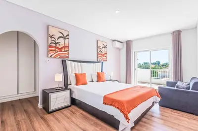a bedroom with a king sized bed and a couch at Villa Corcovada in Albufeira