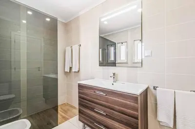 a bathroom with a sink and a shower and a mirror at Villa Corcovada in Albufeira