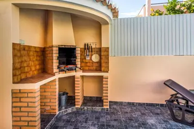 an outdoor kitchen with a brick fireplace on the side of a building at Villa Timoneiro in Galé