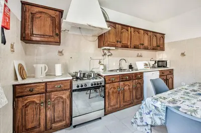 a kitchen with wooden cabinets and a stove top oven at Villa Timoneiro in Galé