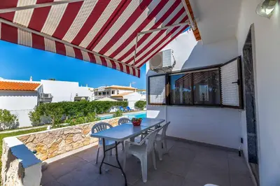 a table and chairs on a patio with an umbrella at Villa Rosa dos Ventos in Galé