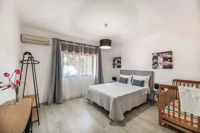 a bedroom with a bed and a window and a crib at Villa Rosa dos Ventos in Galé