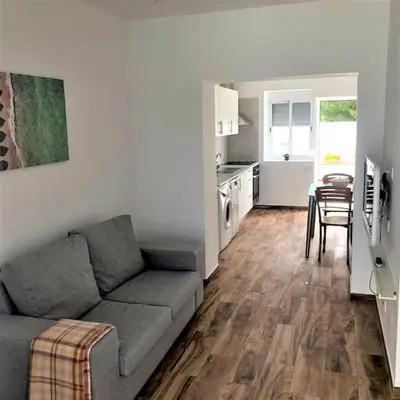a living room with a couch and a table and a kitchen at Casa Vitoria - Olhos de Agua - Albufeira in Roja- Pé