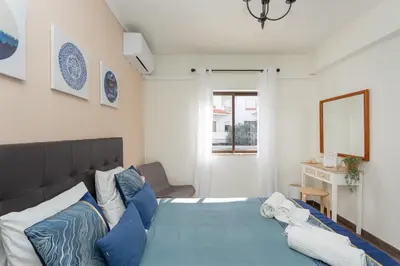 a bedroom with a bed with blue and white pillows at Algarvian Experience - Sun, Beach and Pool in Albufeira