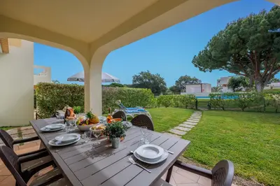 a wooden table on a patio with a view of a yard at Meadow View Retreat in Albufeira