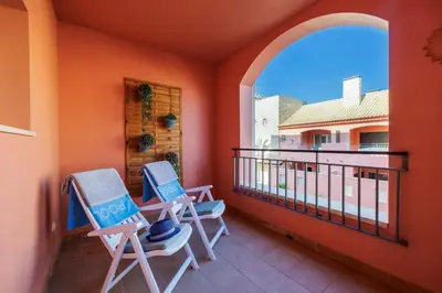 a balcony with two chairs and a window at Avenue Apartment Vilamoura in Quarteira