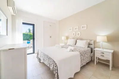a white bedroom with a bed and a window at Villa Catarino in Albufeira