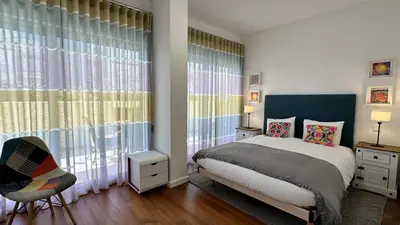 a bedroom with a bed and a chair and windows at Harmony by Check-in Portugal in Albufeira