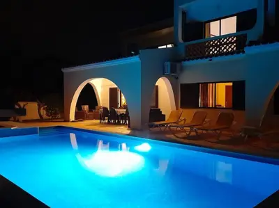 a swimming pool in front of a house at night at Villa Palmeiras - Serene Private Villa in Albufeira