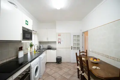 a kitchen with a wooden table and a kitchen with white cabinets at Villa Angélica - Cozy Homestay in Albufeira