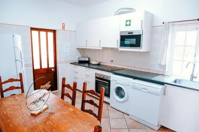a kitchen with a table and a washing machine at Villa Angélica - Cozy Homestay in Albufeira