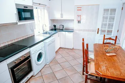 a kitchen with a table and a washing machine at Villa Angélica - Cozy Homestay in Albufeira