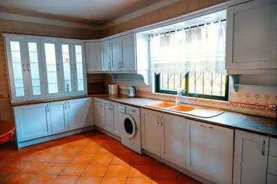 a kitchen with white cabinets and a washing machine at Villa Miracampo - Elegant Secret in Albufeira