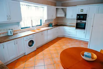 a kitchen with white cabinets and a wooden table at Villa Miracampo - Elegant Secret in Albufeira