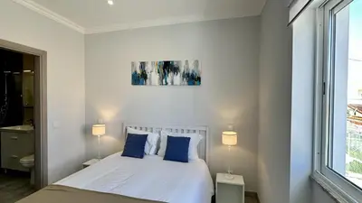 a white bedroom with a bed with blue pillows at Hibisco 2 by Check-in Portugal in Albufeira