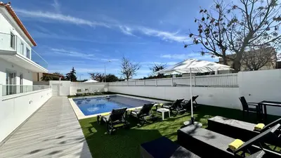 a backyard with a swimming pool with chairs and an umbrella at Hibisco 2 by Check-in Portugal in Albufeira