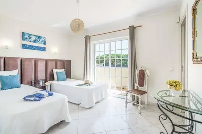 a hotel room with two beds and a glass table at Villa Judite in Albufeira