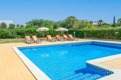 a swimming pool with lounge chairs and umbrellas at Villa Judite in Albufeira