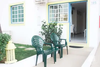 two green chairs sitting on the front porch of a house at Apartamentos Sereia da Oura in Albufeira