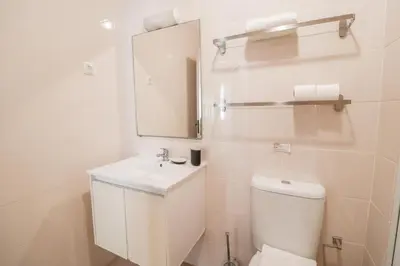 a white bathroom with a toilet and a mirror at Old Village Vilamoura in Quarteira