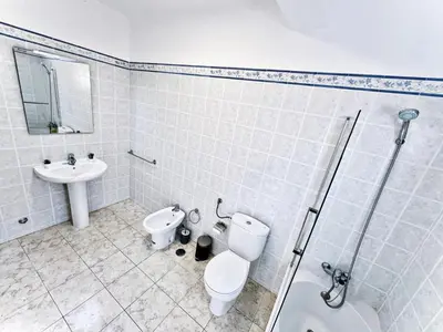a white bathroom with a toilet and a sink at Flat Luxuous Praia da Oura in Albufeira