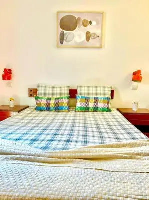 a bedroom with a bed with checked sheets and pillows at Resort Albufeira T1, Praia da Oura in Albufeira