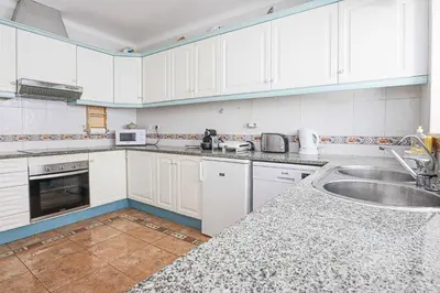 a kitchen with white cabinets and a sink at Villa Vivienda Rosa in Albufeira