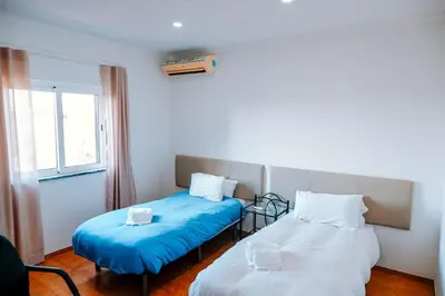 a room with two beds with blue sheets and a window at Villa dos Sonhos - Wide Dreams in Albufeira