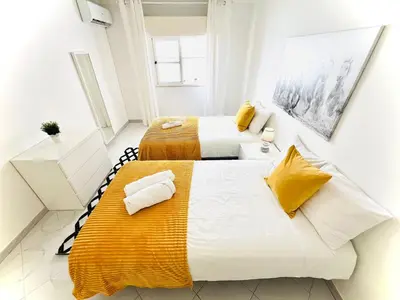 two beds in a small room with yellow and white at Apartamento 5 Estrelas Praia da Oura in Albufeira