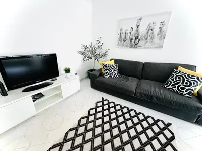 a living room with a black couch and a flat screen tv at Apartamento 5 Estrelas Praia da Oura in Albufeira