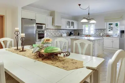a white kitchen with a table and chairs and a kitchen with at Villa Lisianto in Albufeira