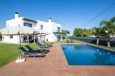 a house with a swimming pool with chairs and an umbrella at Villa Dala in Albufeira