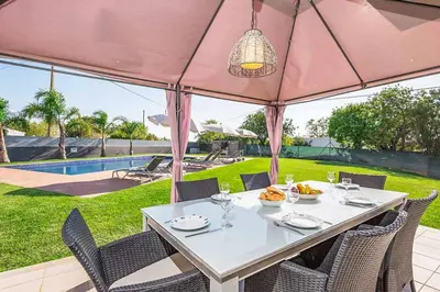 a dining table with chairs and a pink umbrella at Villa Dala in Albufeira