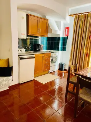 a kitchen with wooden cabinets and a tile floor at Resort Albufeira T1, Praia da Oura in Albufeira