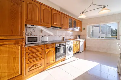 a kitchen with wooden cabinets and a washer and dryer at Blue Horizon Apartment by HelloVacations in Albufeira