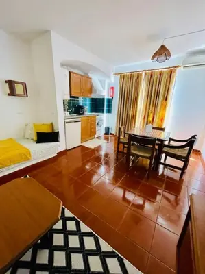 a living room with a dining table and a kitchen at Resort Albufeira T1, Praia da Oura in Albufeira