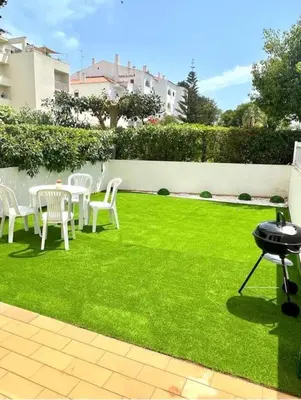 a lawn with white chairs and tables and a fence at Amazing Studio Flat Albufeira in Albufeira